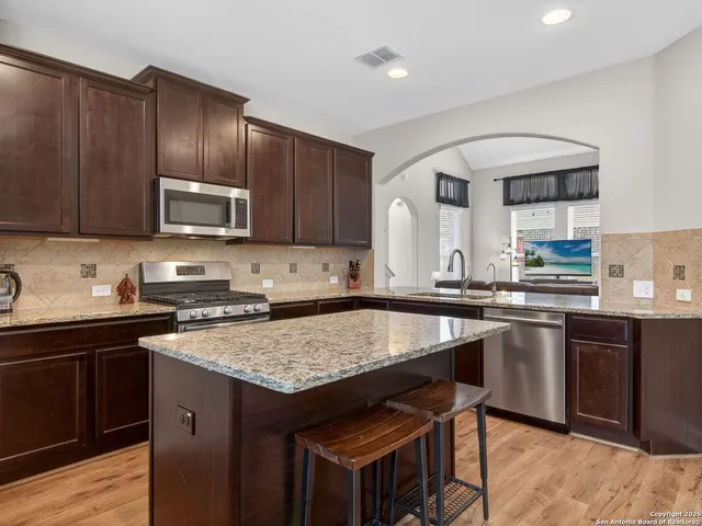 a kitchen with granite countertop wooden cabinets a stove top oven a sink and dishwasher