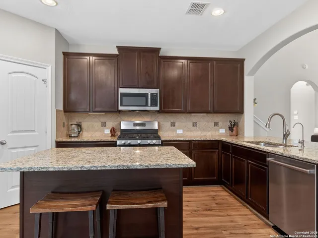 a kitchen with kitchen island granite countertop a sink cabinets and stainless steel appliances