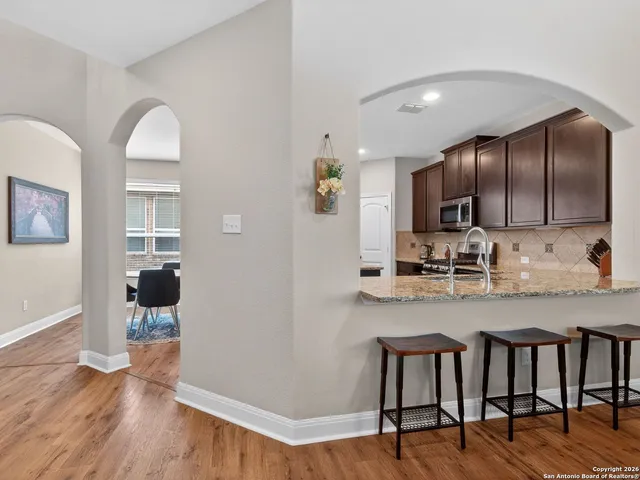 a kitchen with refrigerator and wooden floor