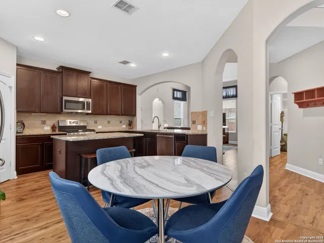 a kitchen with a dining table chairs and refrigerator