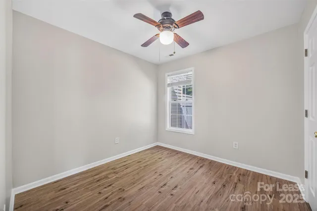 an empty room with wooden floor and ceiling fan