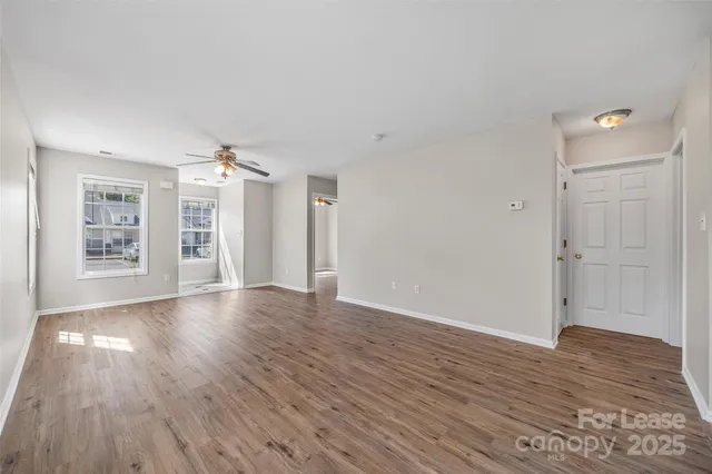 an empty room with wooden floor cabinet and windows