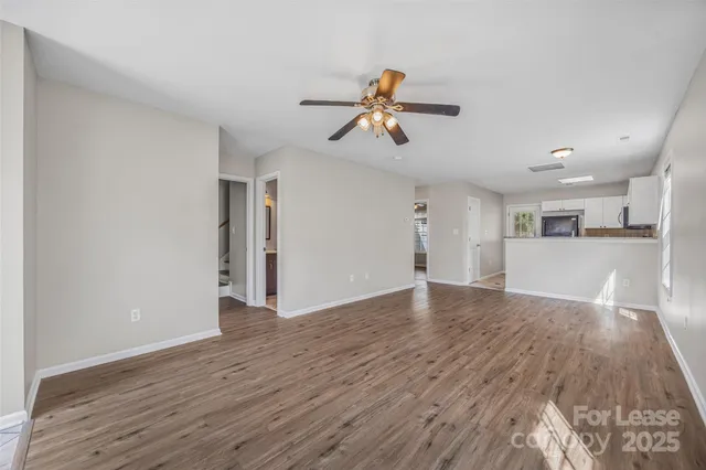 a view of empty room with wooden floor and ceiling fan