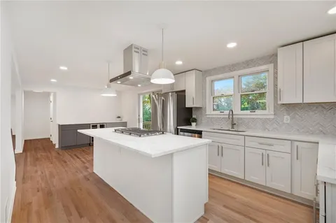 a kitchen with stainless steel appliances a sink a stove a refrigerator and white cabinets