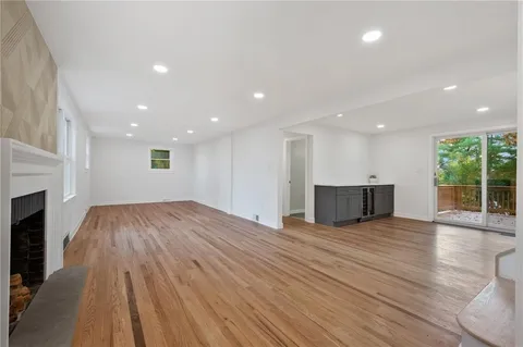 a view of an empty room with wooden floor and a fireplace