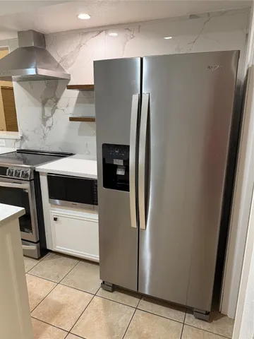 a kitchen with stainless steel appliances a refrigerator a stove and white cabinets