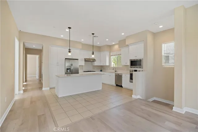 a large white kitchen with kitchen island a sink a stove a refrigerator and white cabinets