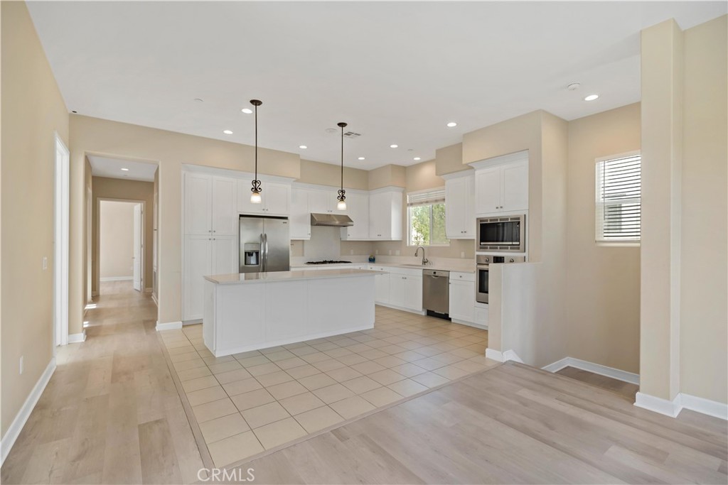 199 Follyhatch Irvine, CA 92618 - Photo 13 of 32 a large white kitchen with kitchen island a sink a stove a refrigerator and white cabinets