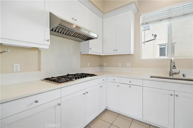 a kitchen with white cabinets and a stove a sink
