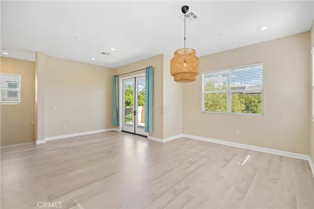 a view of an empty room with window and wooden floor