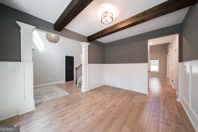 an empty room with wooden floor fireplace and windows