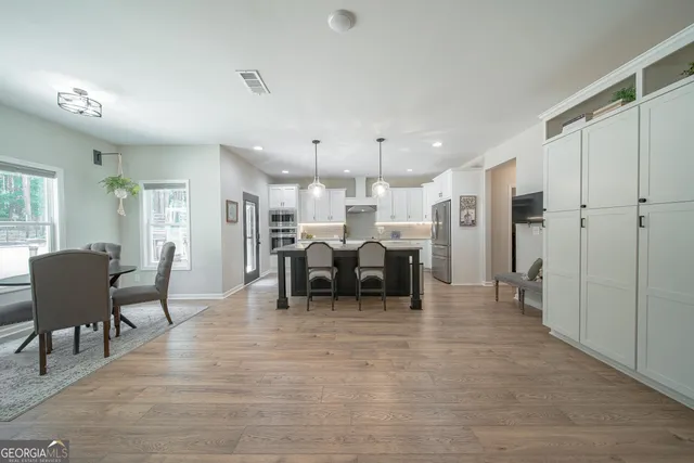 a kitchen with stainless steel appliances kitchen island granite countertop a table chairs and a refrigerator