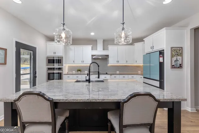 a kitchen with granite countertop white cabinets and stainless steel appliances