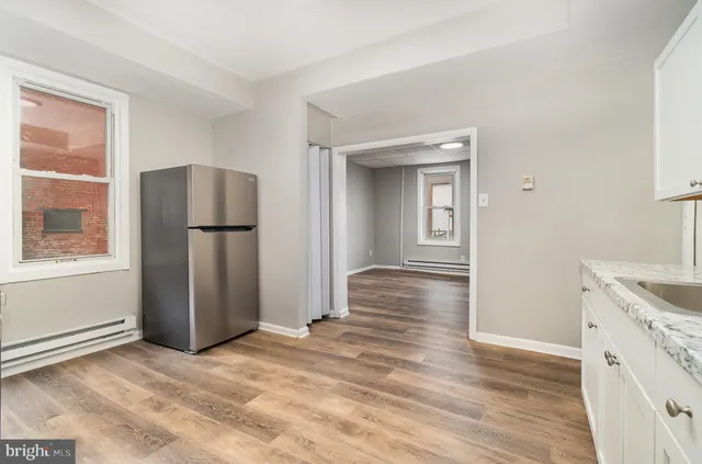 a view of a kitchen with wooden floor and refrigerator
