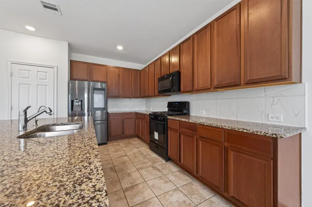 a kitchen with granite countertop a sink stove and microwave