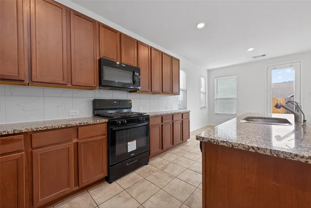 a view of kitchen with granite countertop cabinets a sink and a refrigerator