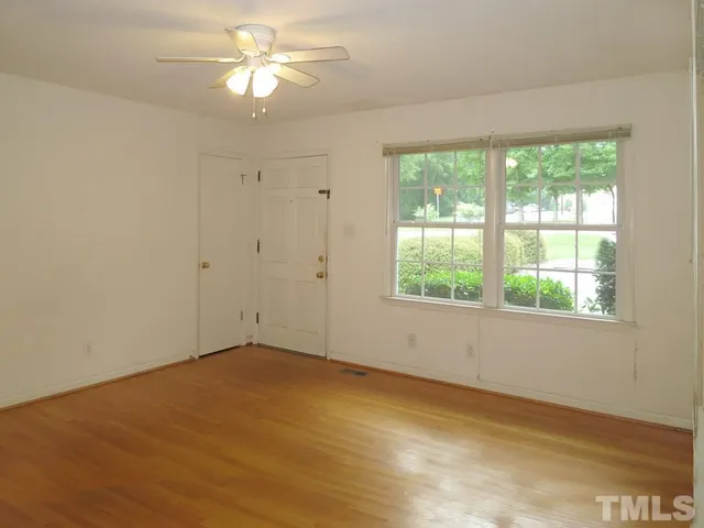 an empty room with a window and a fan
