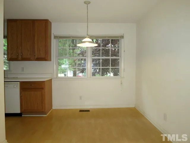 an empty room with windows and kitchen view