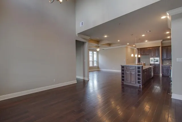 a big room with wooden floors and a kitchen view