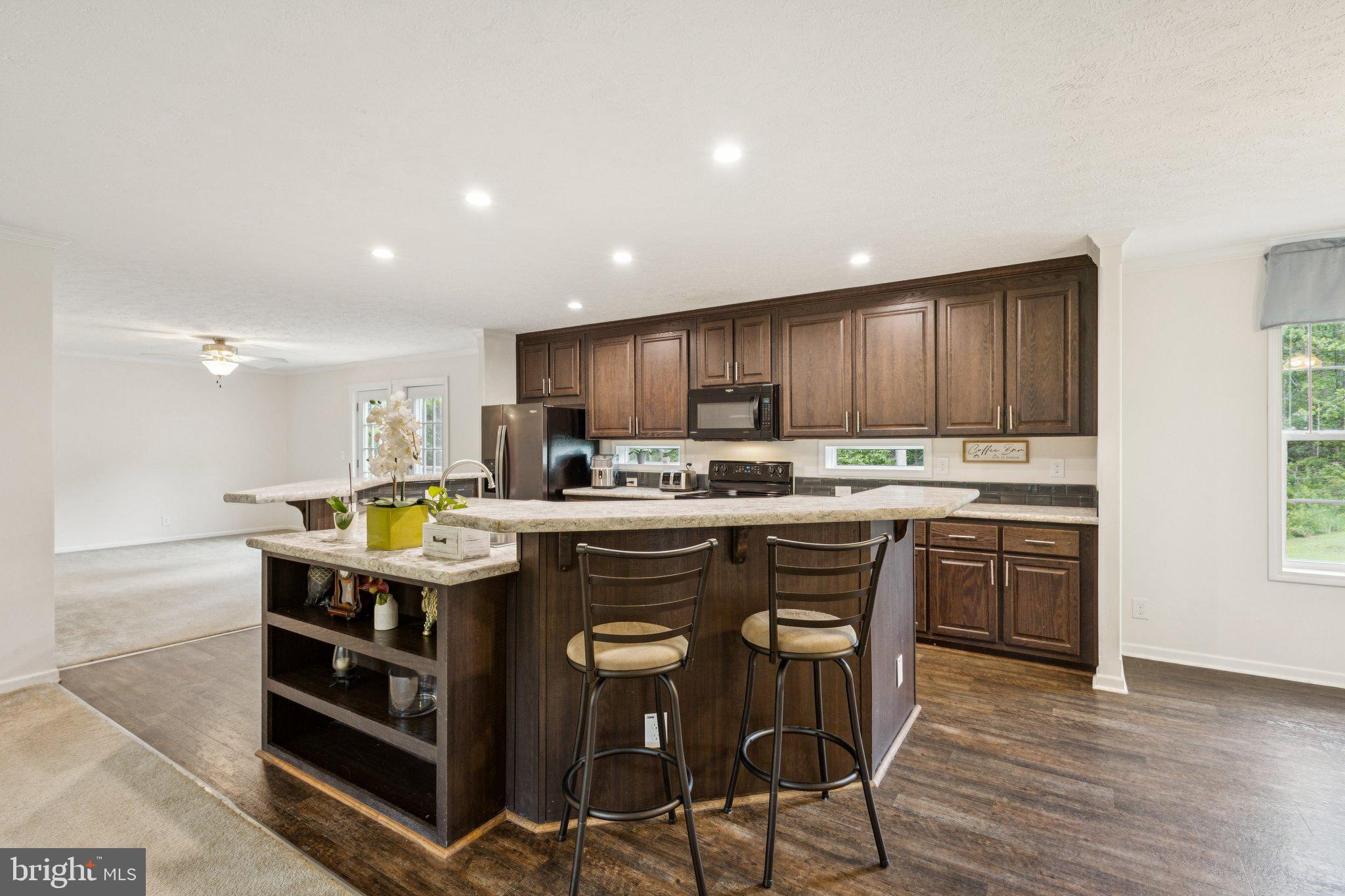 13153 Stonehouse Mountain Road Culpeper, VA 22701 - Photo 11 of 45 a kitchen with stainless steel appliances granite countertop a table chairs sink refrigerator and cabinets