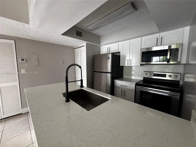a kitchen with granite countertop a refrigerator and a stove top oven
