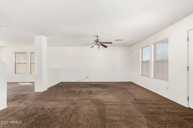 an empty room with windows and ceiling fan view