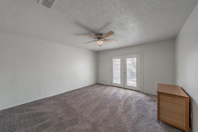 an empty room with windows and ceiling fan