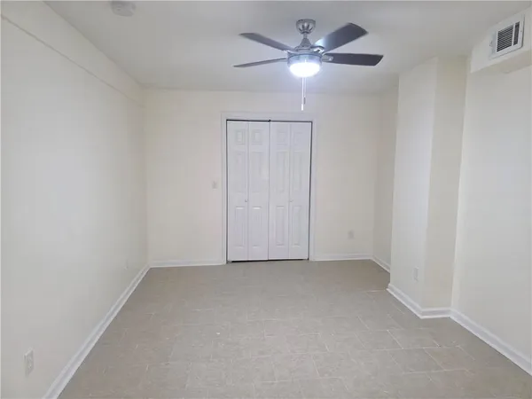 an empty room with a chandelier fan and windows