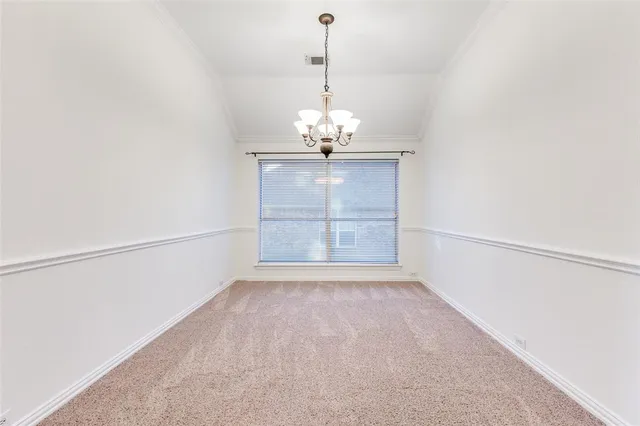 an empty room with chandelier fan and windows