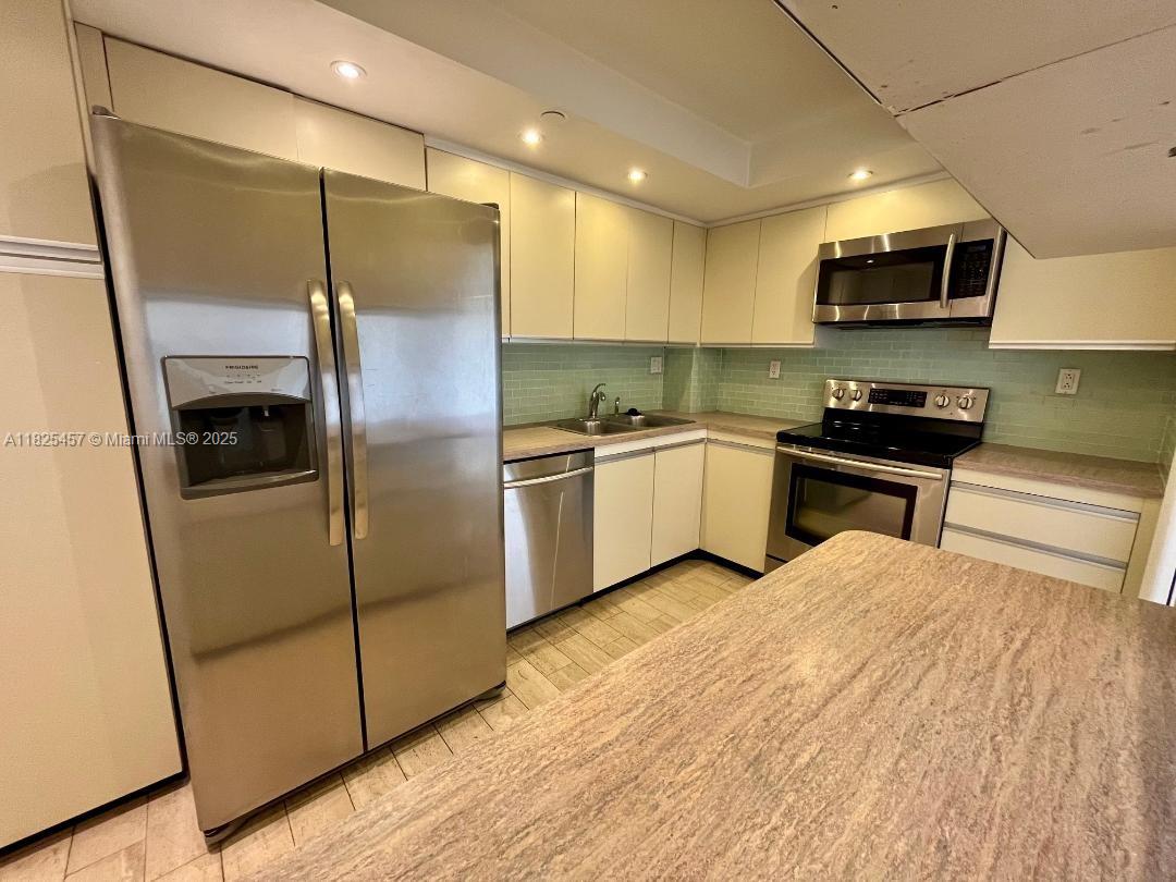 1000 Quayside Terrace, Unit 1009 Miami, FL 33138 - Photo 7 of 50 a kitchen with stainless steel appliances granite countertop a refrigerator a sink a stove top oven a counter space and cabinets