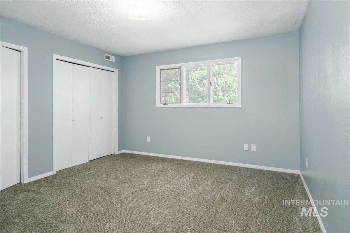 1401 Chokecherry Drive Pocatello, ID 83204 - Photo 33 of 46 Carpeted room featuring a double bi-fold closet, additional single bi-fold closet, and a three-pane window with white trim