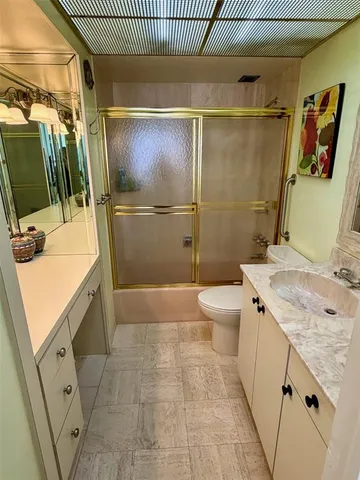 a bathroom with a granite countertop sink a toilet and shower