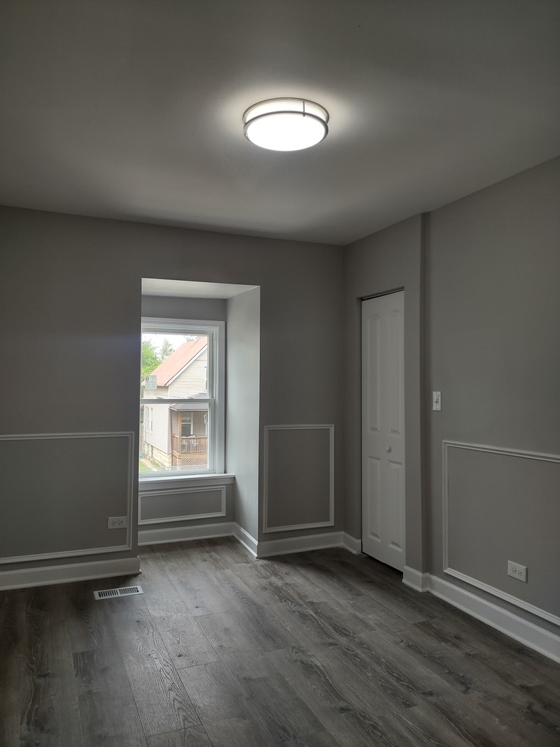11531 South Perry Avenue Chicago, IL 60628 - Photo 12 of 16 an empty room with wooden floor and windows