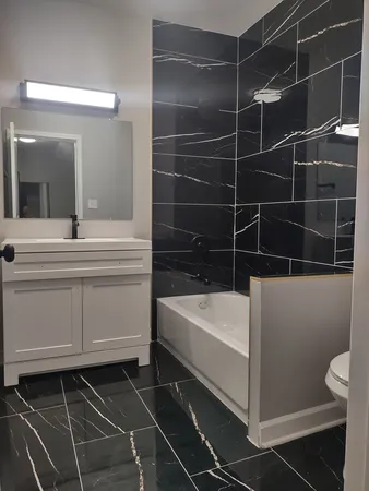 a bathroom with a bathtub a sink a toilet and a mirror