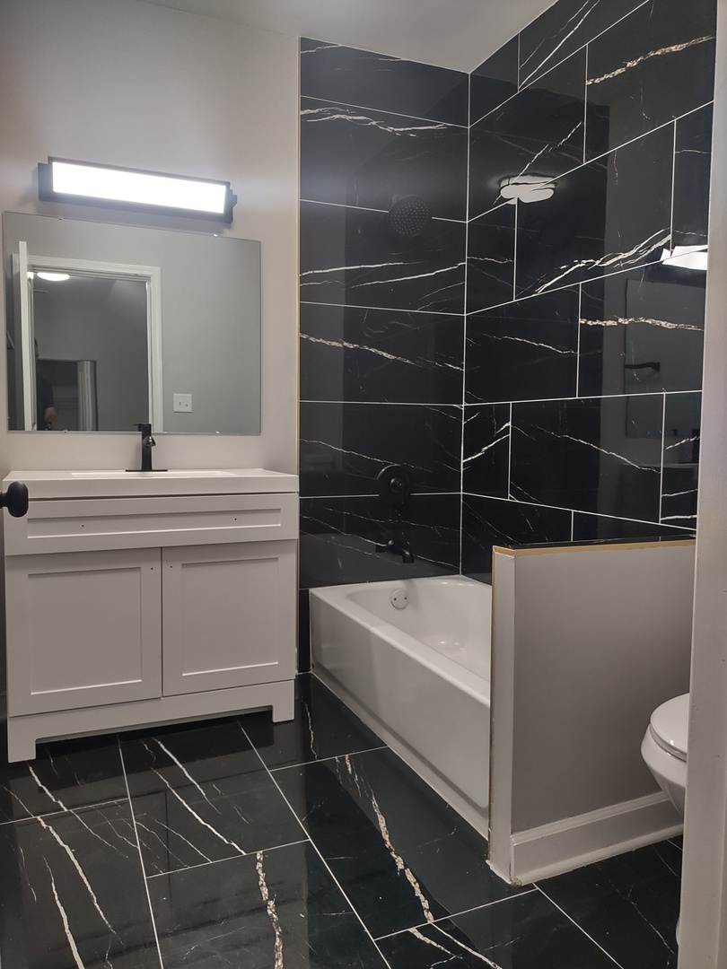 11531 South Perry Avenue Chicago, IL 60628 - Photo 5 of 16 a bathroom with a bathtub a sink a toilet and a mirror