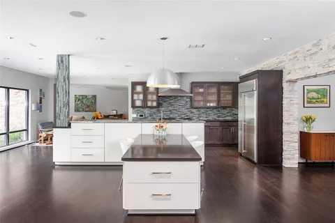 a kitchen with stainless steel appliances kitchen island granite countertop a stove a sink and white cabinets with wooden floor