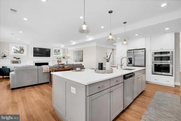 a large kitchen with stainless steel appliances a large counter top a sink a stove and a refrigerator