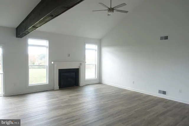 an empty room with wooden floor a fireplace and windows