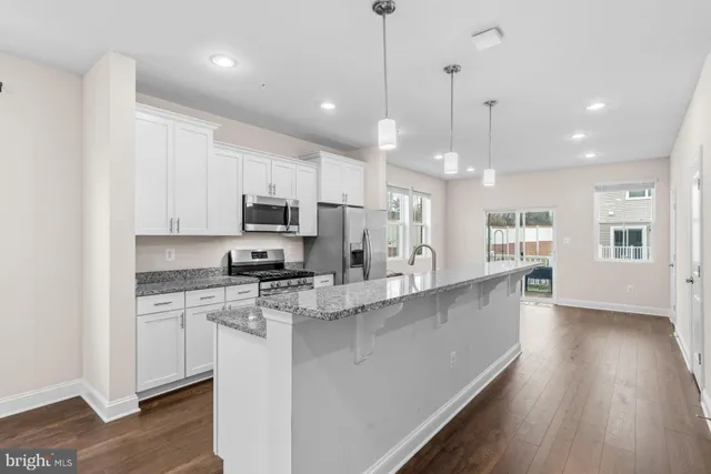 a large kitchen with stainless steel appliances granite countertop a stove a sink a refrigerator and a granite counter tops with wooden floors