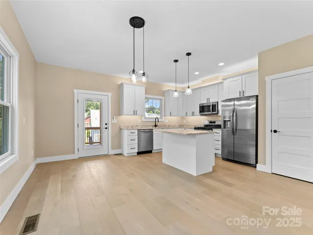 a large kitchen with stainless steel appliances kitchen island a stove a sink dishwasher a refrigerator and a counter space