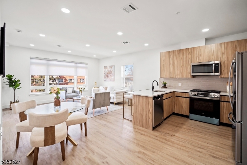 310 West Jersey Street, Unit 404 Elizabeth, NJ 07202 - Photo 1 of 14 a large kitchen with stainless steel appliances granite countertop a stove a sink a refrigerator a dining table and chairs with wooden floor