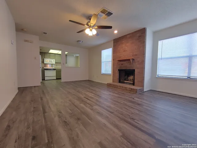 an empty room with wooden floor fireplace and windows