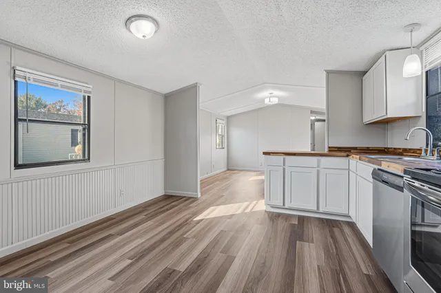 a view of a kitchen with a sink and dishwasher stove top oven with wooden floor
