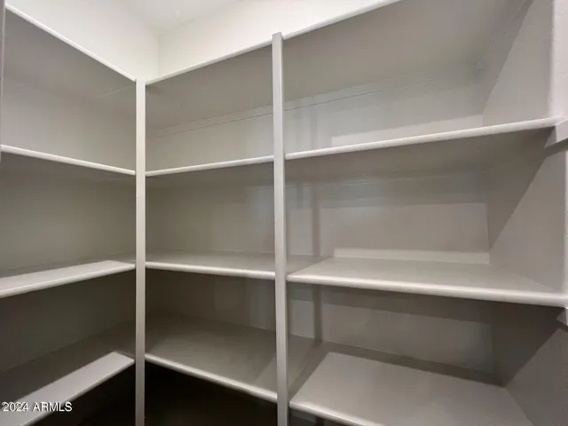 an empty room with wooden floor chandelier fan and windows