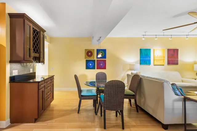 a kitchen with stainless steel appliances granite countertop a stove a refrigerator a dining table and chairs with wooden floor