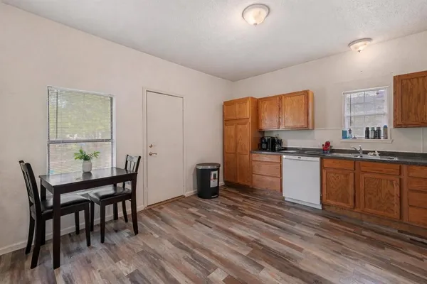 a kitchen with granite countertop wooden floors cabinets a dining table and appliances