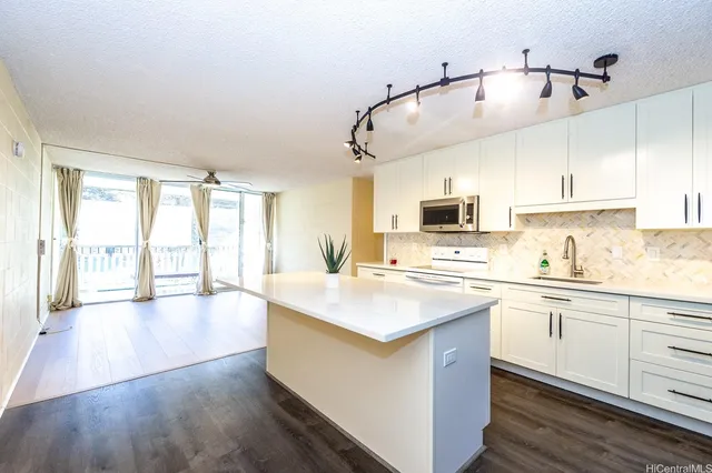 a kitchen with stainless steel appliances a stove top oven a sink dishwasher and a refrigerator with wooden floor