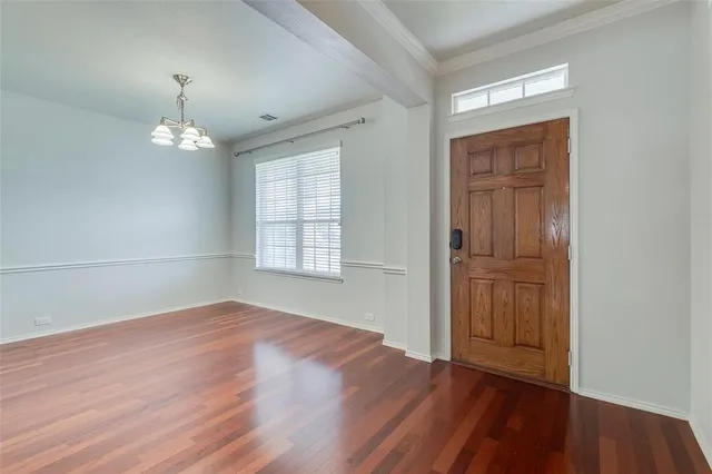 an empty room with wooden floor cabinet and windows