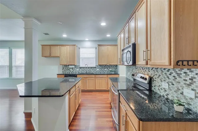 a kitchen with granite countertop a sink a stove and cabinets