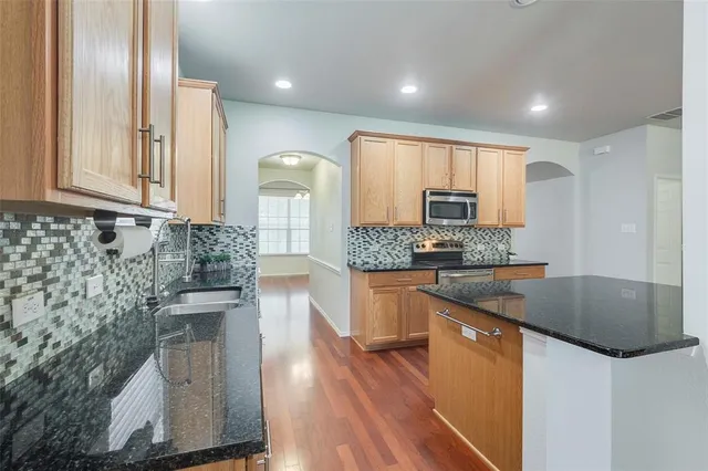a kitchen with granite countertop a sink a stove and cabinets